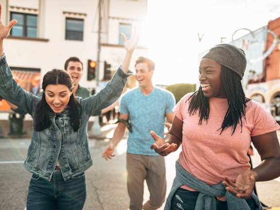 A group of people are walking down a street with their arms in the air.