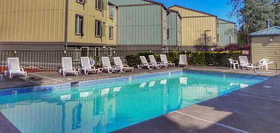 A pool with sun loungers in front of a building.