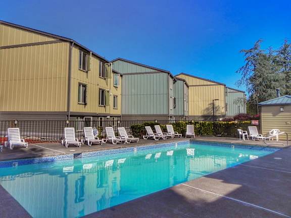 A pool with sun loungers in front of a building.