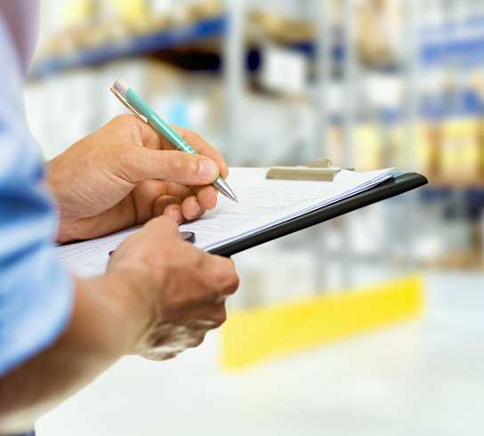 Person Checking Warehouse Inventory on Clipboard