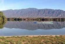 A long bridge over a body of water with mountains in the background.