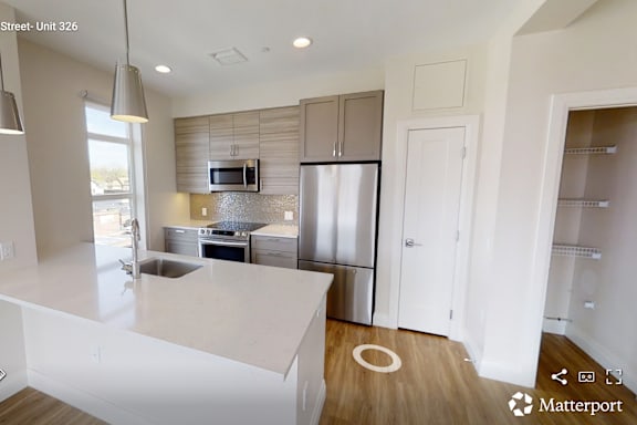 A modern kitchen with a white countertop and stainless steel appliances.
