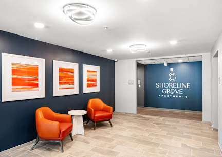 a lobby with orange chairs and a blue wall with three pictures at Shoreline Grove Apartments in Branford CT. at Shoreline Grove Apartments in Branford CT.