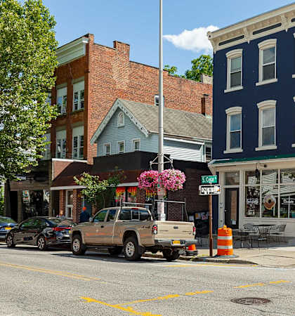 A street view with cars parked on the side of the road and buildings in the background.