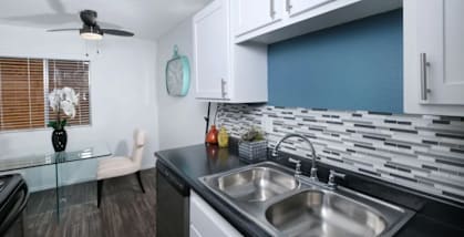 A modern kitchen with a black countertop and a stainless steel sink.