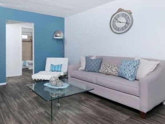 A living room with a pink couch and a glass coffee table.
