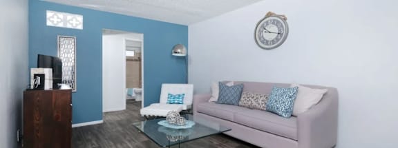 A living room with a pink couch and a glass coffee table.