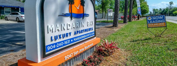 A sign for Mandarin Bay Luxury Apartments is displayed in front of a building.