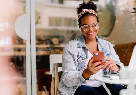 A woman is sitting at a table with a laptop and a smartphone in her hands at Apex, Colorado Springs, CO, Colorado, 80923