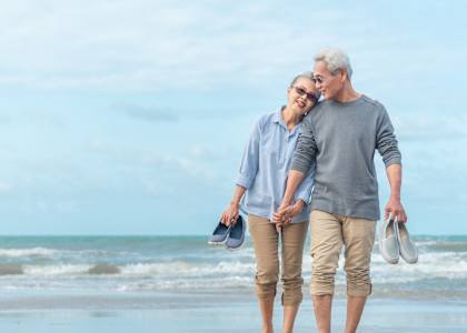 a man and a woman walking on the beach with shoes in their hands