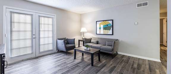 A living room with a grey couch and a painting on the wall.