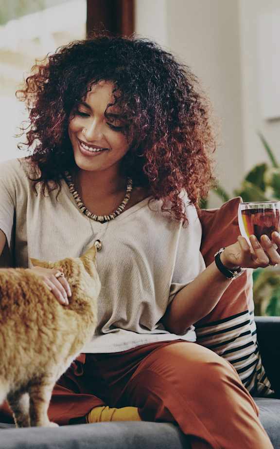 A woman is sitting on a couch with a cat on her lap.