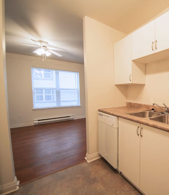 A modern kitchen with a stainless steel refrigerator and wooden flooring.