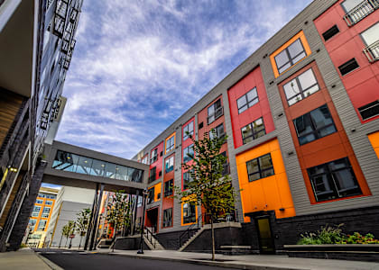 A modern building with orange and grey exterior and a tree in front.at Center Square Lofts East, Pennsylvania, 18101