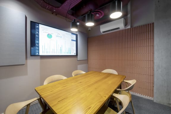 a meeting room with a table and chairs and a projection screen on the wall