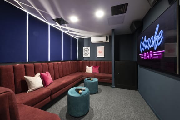 a cinema room with red couches and blue walls and a neon sign