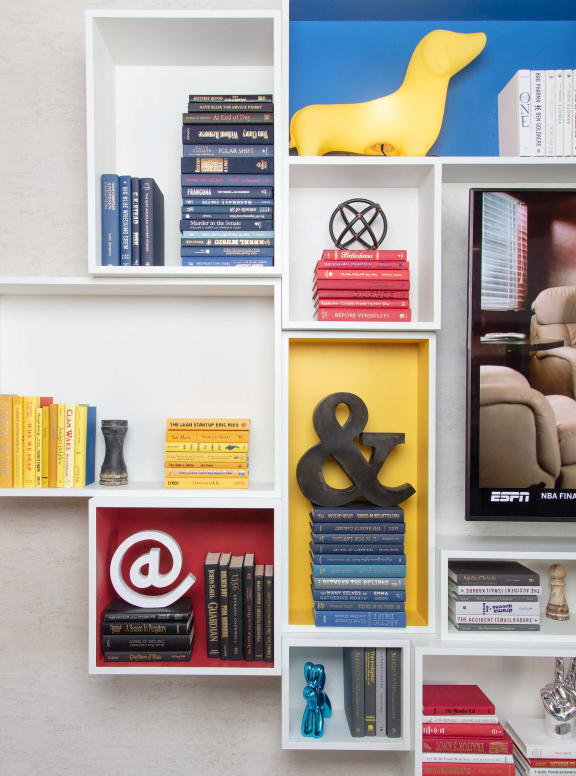 a bookshelf filled with books and a yellow bird on top at The Enclave, Jersey City, New Jersey