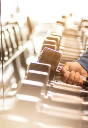a man choosing a dumbbell on a gym cardio machine