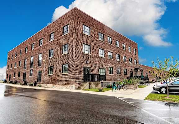 A large red brick building with a black gate in front.