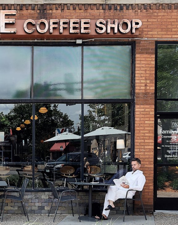 a man sitting at a table outside of a coffee shop