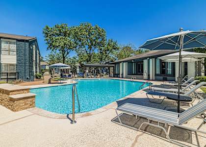 a swimming pool with chairs and umbrellas next to a house