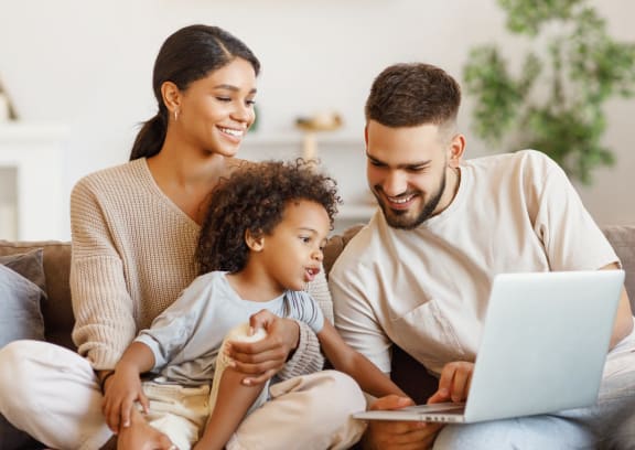 a family sitting on a couch looking at a laptop computer at Allure at Edinburgh, Chesapeake, VA, 23322