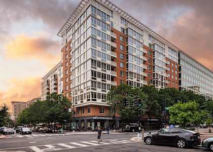 A large building with a lot of windows is in the middle of a street.