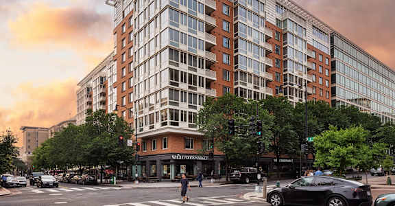A large building with a lot of windows is in the middle of a street.
