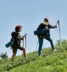 Two people hiking up a hill with backpacks.