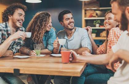 A group of people are sitting around a table, laughing and enjoying each other's company.