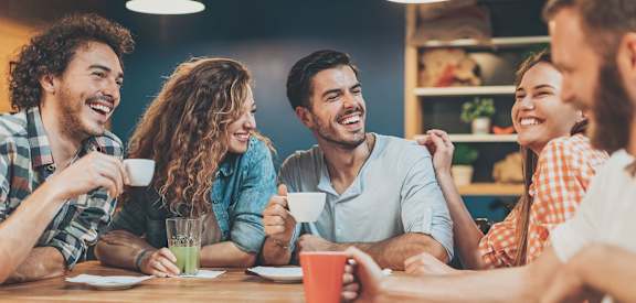 A group of people are sitting around a table, laughing and enjoying each other's company.
