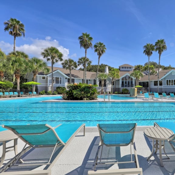 a large swimming pool with lounge chairs and tables at The Monroe Apartment Homes, Florida, 32303