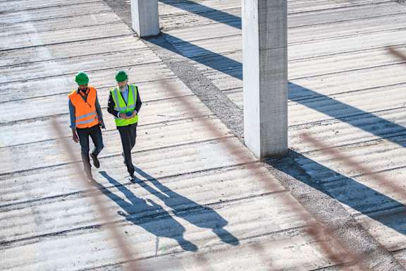 two construction workers walking on a wooden boardwalk