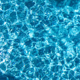 a woman swimming in a pool with blue water
