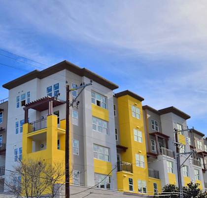 a row of apartment buildings with yellow and white facade and a blue sky