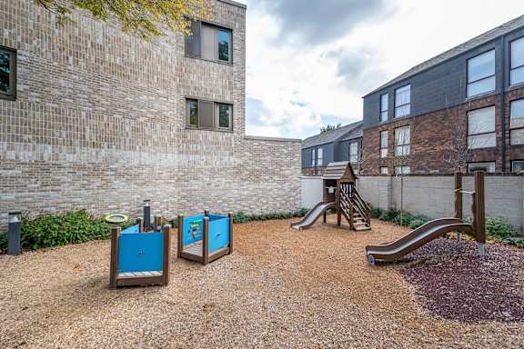 an outdoor playground with slides and swings at an apartment building