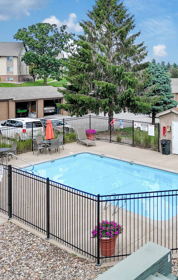 A black fence surrounds a blue swimming pool.
