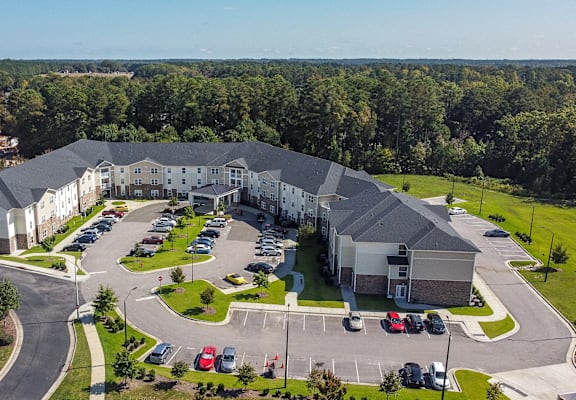 an aerial view of an apartment building with parking lot and cars