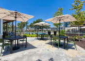 Thumbnail 8 of 28 - a patio with tables and umbrellas and chairs and a pool at Estraya Boerne, Boerne