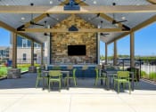 Thumbnail 12 of 28 - a patio with tables and chairs under a pavilion with a fireplace
