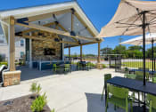 Thumbnail 6 of 28 - the preserve at ballantyne commons covered patio with tables and chairs and a fireplace at Estraya Boerne, Boerne