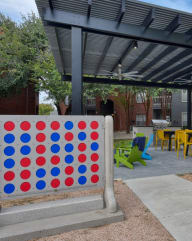 a large red and blue game board next to a pergola in a courtyard