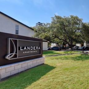 a grassy area in front of a building with a sign that says landera apartments