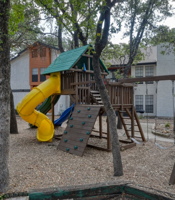 a playground with a large yellow slide and a wooden climbing structure