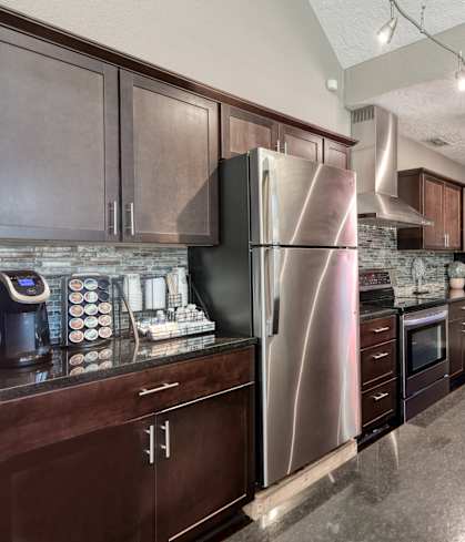 a kitchen with dark cabinets and a stainless steel refrigerator