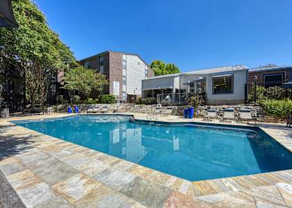 a swimming pool with lounge chairs and a house in the background