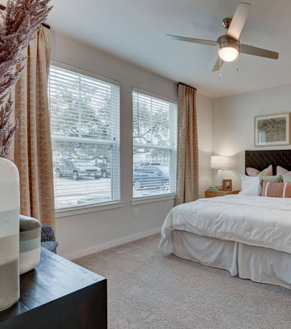 A bedroom with a large bed and a ceiling fan.