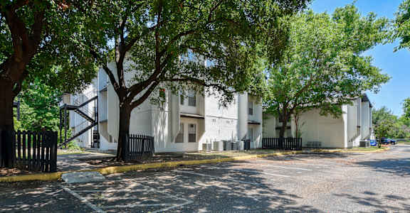 a street view of a white apartment building with trees