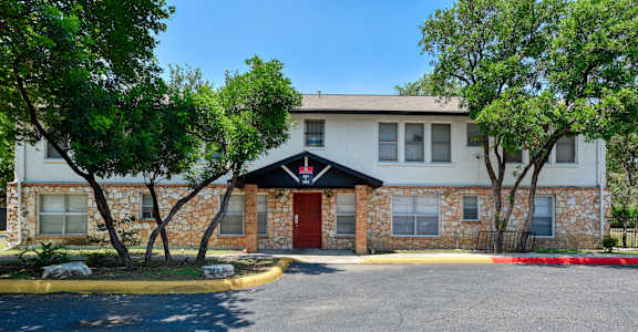 a brick building with a red door and trees in front of it
