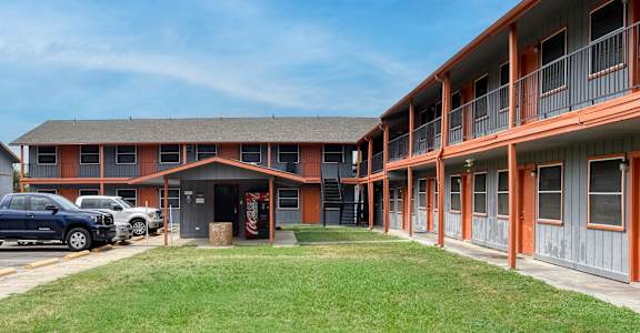 an exterior view of a building with a lawn and a parking lot at The Crossings at Montrose Apartments, San Antonio, Texas
